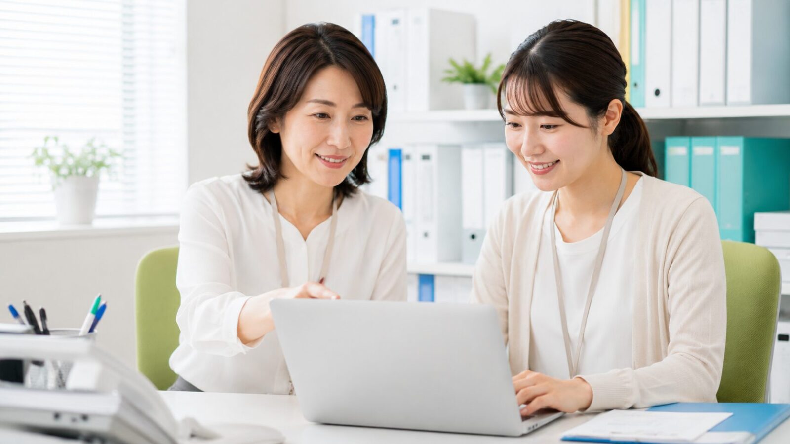 先輩が新人事務員に業務を教える様子